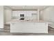 Bright, open kitchen featuring a large island, white cabinets, and stainless steel appliances at 37549 W San Clemente St, Maricopa, AZ 85138