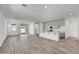 Bright, open-concept living space with wood-look flooring, leading to a modern kitchen with stainless appliances at 37549 W San Clemente St, Maricopa, AZ 85138
