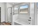 Bright bathroom featuring glass-enclosed shower and soaking tub next to a window at 37551 W Patterson St, Maricopa, AZ 85138