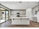 Modern kitchen boasts an island, white cabinets, stainless steel appliances, and backyard access at 37551 W Patterson St, Maricopa, AZ 85138