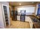Well-lit kitchen featuring stainless steel appliances, white cabinets, and tile flooring, providing ample counter space at 44944 W Miramar Rd, Maricopa, AZ 85139