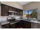 Modern kitchen with dark cabinets, granite countertops, and a view to the pool at 4753 E Bighorn Ave, Phoenix, AZ 85044