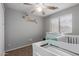 A Bedroom with a crib, ceiling fan, changing table, and natural light from the window at 5253 E Hilton Ave, Mesa, AZ 85206