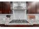 Close up of stovetop and vent over a granite countertop in a modern kitchen at 5253 E Hilton Ave, Mesa, AZ 85206