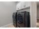 Modern laundry room includes front loading washer and dryer and white upper cabinets at 5515 E Dale Ln, Cave Creek, AZ 85331
