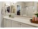 Bathroom boasting dual sinks, white cabinetry, decorative hardware and a mirrored wall at 5810 E Nora St, Mesa, AZ 85215