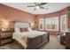 Charming primary bedroom with a decorative ceiling fan, carpet and two large windows with shutters at 5810 E Nora St, Mesa, AZ 85215