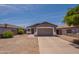 Single-story home boasts a large driveway, desert landscaping, neutral tones, and attached two-car garage at 719 E Broadway Ave, Apache Junction, AZ 85119