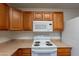 Close-up of a kitchen with white stove and microwave, and oak cabinets at 719 E Broadway Ave, Apache Junction, AZ 85119