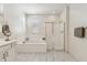 Bright bathroom features a soaking tub, glass shower, and white marble tile flooring at 732 W Flintlock Way, Chandler, AZ 85286