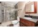 Tiled bathroom features glass shower, toilet and vanity with dark countertop and framed mirror at 8238 E Jackrabbit Rd, Scottsdale, AZ 85250