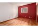 Bedroom featuring wood laminate flooring, red accent wall, and window at 8238 E Jackrabbit Rd, Scottsdale, AZ 85250