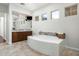 Bright bathroom features a soaking tub with mosaic tile surround, dual sink vanity, and warm tile flooring at 8240 E Wingspan Way, Scottsdale, AZ 85255