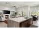 Modern kitchen featuring a large island, dark cabinets, and an open view into the living area at 8240 E Wingspan Way, Scottsdale, AZ 85255