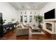 Bright living room with hardwood floors, a cozy fireplace, and multiple windows offering scenic views at 8240 E Wingspan Way, Scottsdale, AZ 85255