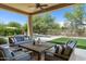 Covered outdoor patio with comfortable seating, ceiling fan, and views of the pool and landscaped yard at 8240 E Wingspan Way, Scottsdale, AZ 85255