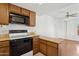 Well-lit kitchen featuring wood cabinets, black microwave, electric range, and a ceiling fan in the connected room at 8414 N Central Ave # B, Phoenix, AZ 85020