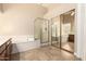 Bathroom featuring a glass-enclosed shower, soaking tub, and vanity with neutral countertops, exuding tranquility at 8627 W Morrow Dr, Peoria, AZ 85382