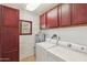 Bright laundry room with white brick walls and red cabinets features modern washer and dryer at 920 N 104Th St, Mesa, AZ 85207