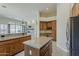 Open kitchen with granite countertops, wood cabinets, a center island, and a view of the stone fireplace at 9562 E Cavalry Dr, Scottsdale, AZ 85262
