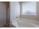 Bathroom featuring a soaking tub with tile surround and natural light from the window at 10649 W Alvarado Rd, Avondale, AZ 85392