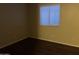 A cozy bedroom featuring wood-look floors, a window with blinds, and neutral walls at 10649 W Alvarado Rd, Avondale, AZ 85392
