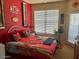 Bright bedroom with a large window, red walls, and floral bedding, creating a cozy and inviting space at 14950 W Mountain View Blvd # 5303, Surprise, AZ 85374