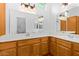 Bright bathroom featuring double sinks with warm wood cabinetry, a large mirror, and tiled floors at 16620 S 48Th St # 79, Phoenix, AZ 85048