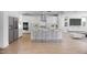A modern kitchen featuring white cabinets, stainless steel appliances, a center island with seating, and open to a cozy living area at 16810 W Yucatan Dr, Surprise, AZ 85388