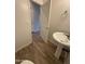 Close-up of half bath with pedestal sink, wood-look tile flooring, and a view of the doorway at 1730 W Pollack St, Phoenix, AZ 85041