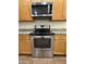 Close-up of stainless steel range and microwave with light wood cabinets and granite countertops at 1738 W Pollack St, Phoenix, AZ 85041