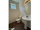 Powder room with a pedestal sink, modern lighting fixture, and decorative oval mirror with wood-look tile floors at 1738 W Pollack St, Phoenix, AZ 85041