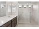 Bathroom with dual sinks, gray cabinetry, and a spacious tiled shower with glass door at 17615 W Palo Verde Dr, Litchfield Park, AZ 85340