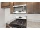 New stainless steel stove and microwave with granite countertops and brown cabinetry at 17615 W Palo Verde Dr, Litchfield Park, AZ 85340