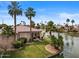 Waterfront home featuring a lush lawn, mature palm trees and covered outdoor seating at 2128 E Clipper Ln, Gilbert, AZ 85234