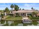Lovely waterfront home featuring lush green lawn, mature palm trees, and a boat docked on the canal at 2128 E Clipper Ln, Gilbert, AZ 85234