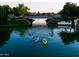 Kayakers paddle along a calm waterfront under a bridge surrounded by lush greenery at 2128 E Clipper Ln, Gilbert, AZ 85234