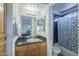 Bathroom featuring a single sink vanity with black countertop, a large mirror, and a shower-tub combo with blue tile surround at 2228 N 52 St # 213, Phoenix, AZ 85008