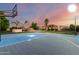 Private basketball court with a rock pool and waterfall in the background beneath a colorful sky at 2892 E Fruitvale Ave, Gilbert, AZ 85297