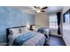 Bright bedroom featuring two beds, a ceiling fan, and a striking blue accent wall at 2940 E Norwood St, Mesa, AZ 85213