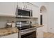 Close-up of stainless steel oven, microwave, and granite counterspace with white cabinets and tiled backsplash at 3058 E Nance St, Mesa, AZ 85213