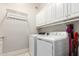 Bright laundry room with washer, dryer, overhead cabinets and hanging rack at 320 N Portland Ave, Gilbert, AZ 85234