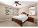 Well-lit bedroom with a ceiling fan, carpet flooring, and a large window offering a scenic view at 35654 N Vidlak Dr, San Tan Valley, AZ 85143