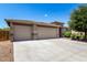 Well-manicured front yard featuring a three-car garage and lush, mature trees and shrubbery at 35654 N Vidlak Dr, San Tan Valley, AZ 85143