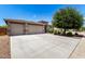 Well-manicured front yard featuring a three-car garage and lush, mature trees and shrubbery at 35654 N Vidlak Dr, San Tan Valley, AZ 85143