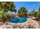 Beautiful pool with palm trees and rock waterfall feature, creating a serene backyard oasis at 35654 N Vidlak Dr, San Tan Valley, AZ 85143