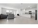 Spacious living room showcasing neutral tile flooring, modern gray furniture, and a view of the adjacent kitchen at 38099 N Stallion St, San Tan Valley, AZ 85140