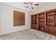 Bedroom with neutral carpet, a ceiling fan, window, and built-in dark wood bookcase at 4336 W Hackamore Dr, Phoenix, AZ 85083