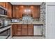 Close up on stainless steel kitchen appliances, granite countertops, dark wood cabinets, and a stylish mosaic tile backsplash at 4354 N 82Nd St # 167, Scottsdale, AZ 85251