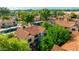 Wide aerial shot of a desert home with a Spanish tile roof surrounded by mature trees and green landscaping at 4901 E Kelton Ln # 1052, Scottsdale, AZ 85254